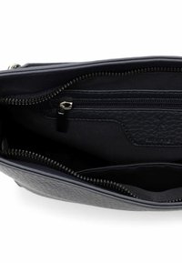 Wnętrze granatowej skórzanej torebki, z kieszenią na zamek, fakturowaną podszewką i podwójnymi przedziałami. Widoczne srebrne okucia zamka.