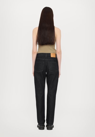 Jeans de mezclilla negra de talle alto con un corte recto, que presentan una etiqueta de cuero en la parte trasera, mostrados desde el reverso, con una textura suave.