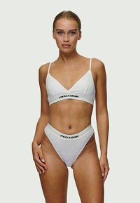 Λευκό δίχρωμο μπικίνι φτιαγμένο από απαλό υλικό. Μπρά ανοιχτού λαιμού σε σχήμα V με λεπτές τιράντες; ψηλόμεσο σλιπ με έμφαση στο λογότυπο "PEGADOR".