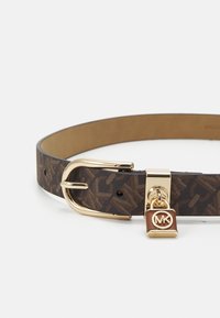 Bruine leren riem met patroon, voorzien van een gouden gesp en charme. Kenmerkt zich door een unieke slotcharme met een reliëflogo en een glad interieur.