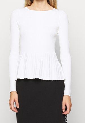 Hvid, ribbet langærmet top med peplum-talje, der har en rund hals og en tekstureret overflade, parret med en sort nederdel med logo-dekoration.
