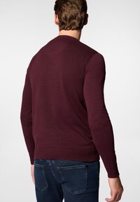 Bordowy sweter z długimi rękawami i okrągłym dekoltem. Posiada ściągacze na rękawach i u dołu. Gładka tekstura, dopasowany krój i minimalne detale.