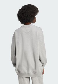 Lys grå oversized sweatshirt, crew neckline, sænkede skuldre, blød tekstur, ribbede cuffs og kant, minimalistisk design.