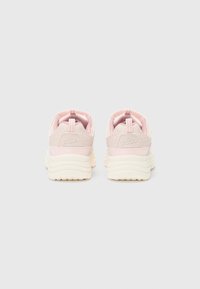 Une paire de baskets FILA rose clair et beige vues de l'arrière avec des semelles blanches imposantes sur un fond clair.