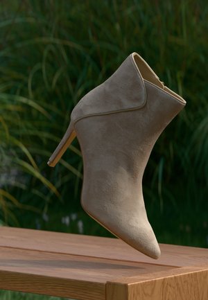 Beige semsket ankelstøvler med spiss tå og slank stilettoskl heel. Sømløst design, glatt tekstur og subtile sømdetaljer.