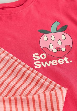 Pink cotton T-shirt featuring a graphic of a smiling, stylized strawberry with seeds, accompanied by the text "So Sweet." Striped accent fabric.
