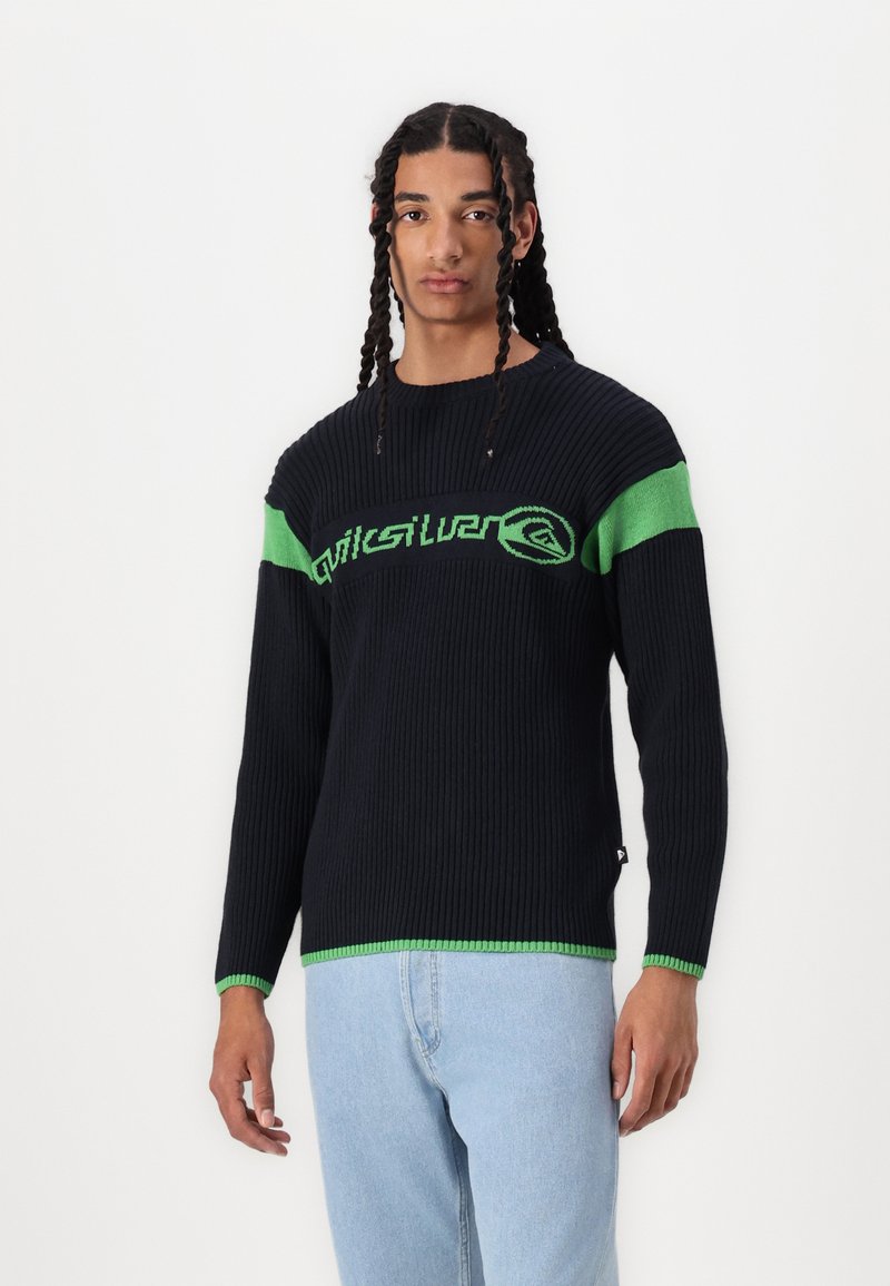Pulover din tricot cu dungi navy, cu accente verzi, având un logo pe piept și o tivă verde contrastantă. Mâneci lungi cu manșete ribbed.