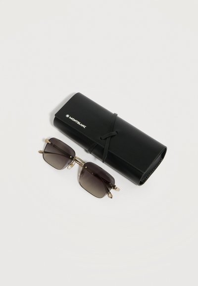 Ορθογώνια γυαλιά ηλίου με σκουρόχρωμους φακούς και χρυσό πλαίσιο δίπλα σε μαύρη δερμάτινη θήκη Montblanc δεμένη με λουρί, σε λευκό φόντο.