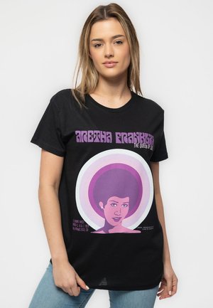 Black cotton t-shirt featuring a graphic print of a woman with an afro, surrounded by concentric circles in purple and white, text reads "Aretha Franklin."