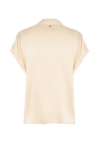 Top beige a maniche corte caratterizzato da una texture morbida, colletto e un'etichetta logo discreta sul retro. Tessuto leggero per il massimo comfort.
