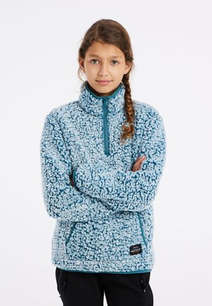 Pullover en polaire bleu clair avec un zip demi-long et un col haut. Présente une surface texturée et duveteuse ainsi que des poches latérales. Logo de la marque au bas.