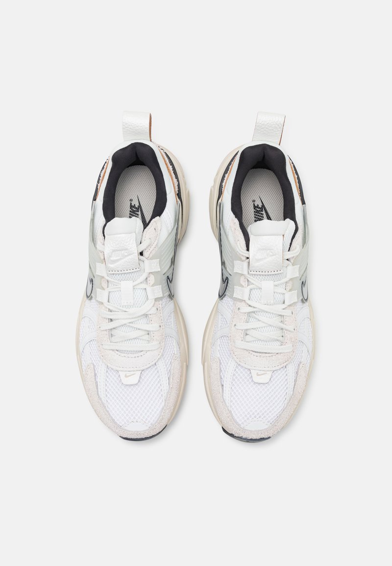 Zapatillas de malla blanca y ante con acentos negros, que cuentan con una lengüeta de talón texturizada, un collar acolchado y múltiples ojetes para los cordones.