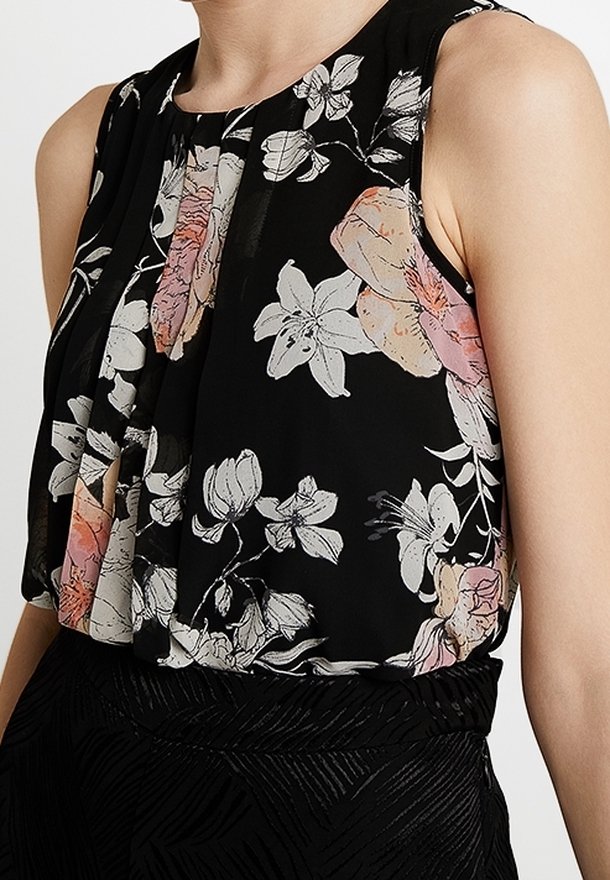 Blouse noire à fleurs avec un design plissé, featuring des fleurs blanches, roses et vertes. Tissu léger et transparent avec un col rond.