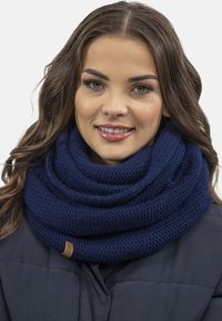 Sötétkék kötött infinity sál, texturált gyapjúból készült, feltekert dizájnnal és egy kis barna bőr márkajellel.