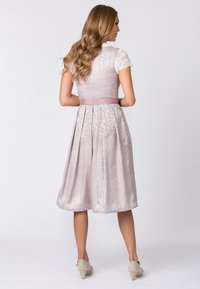 Ein hellrosa Kleid mit Blumenmustern, einem taillierten Oberteil, kurzen Spitzenärmeln und einem plissierten Rock bis zum Knie. Abgerundet mit einem Taillenband.