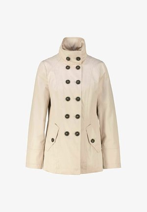 Beige Jacke mit hohem Kragen, doppelt geknöpftem Design, sechs schwarzen Knöpfen und zwei Fronttaschen. Glatte Textur, lange Ärmel.