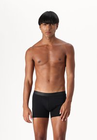 Black boxer briefs made of smooth, stretch fabric. Features a simple design with a snug fit and elastic waistband.