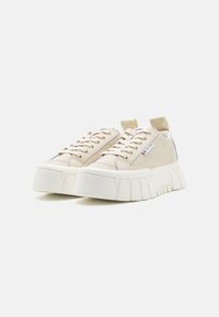 Beżowe sneakersy z masywną białą podeszwą, z sznurówkami, bocznymi akcentami i pętelką na pięcie. Gładka tekstura z detalami w postaci przeszyć.