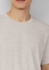 Jasnoszara koszulka z krótkim rękawem, wykonana z miękkiego, lekkiego materiału o subtelnej teksturze i klasycznym okrągłym dekolcie.