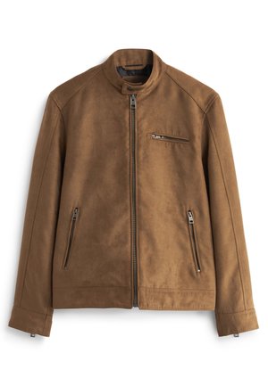 Gros plan d'une veste en daim beige avec une fermeture éclair métallique partiellement fermée et une petite poche zippée sur la poitrine, portée sur un col roulé côtelé crème.