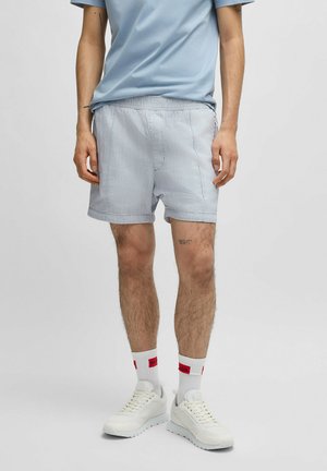 Light blue striped shorts with an elastic waistband, paired with a matching t-shirt and white sneakers. Simple design, casual fabric.