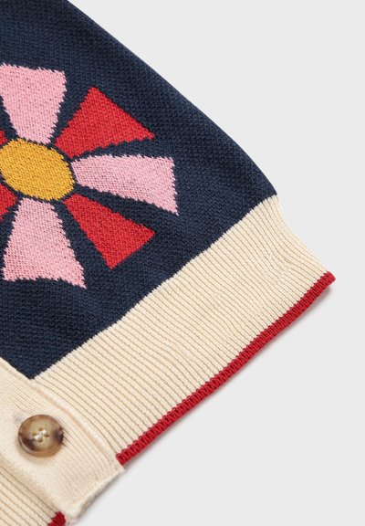 Jersey de punto con base azul marino, un diseño de flores en rosa, rojo y amarillo, con un dobladillo acanalado en color crema y un detalle de botón en el lado.