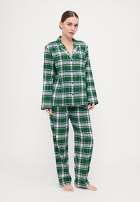 Green and white plaid pajama set, featuring a button-up shirt with long sleeves and matching pants, made from soft fabric with a relaxed fit.