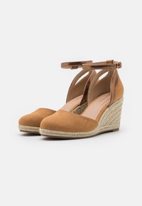 Scarpe con zeppa in suede marrone con cinturini alla caviglia e suola in juta intrecciata, caratterizzate da una punta tondeggiante e una morbida fodera interna.