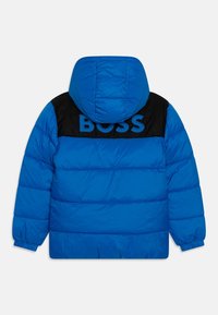 Modrá péřová bunda s kapucí, černý horní zadní panel a výrazné logo "BOSS" v modré barvě. Vybavena elastickými manžetami a prošívanou texturou.