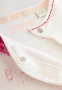 Biała bawełniana koszula z kołnierzykiem z różowymi akcentami i zapięciem na zatrzask, z napisem "BAKER by TED BAKER" wydrukowanym w jasnoróżowym kolorze. Gładka faktura.