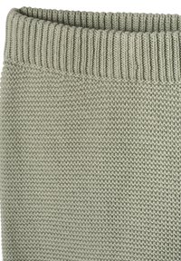 Nahaufnahme eines hellgrau-grünen Strickstoffs mit geripptem Kragen, der das strukturierte Strickmuster und feine Garnschlaufen zeigt.