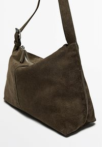 Brown suede shoulder bag with a triangular shape, featuring a zippered pocket and a wide adjustable strap. Textured surface and minimalist design.