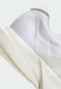 Chaussure de course blanche avec un upper texturé présentant un motif géométrique, une silhouette élancée et une conception légère et respirante.