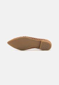 Chaussure plate tissée couleur nude avec un bout pointu et une semelle en caoutchouc, présentant un logo discret sur la partie inférieure.