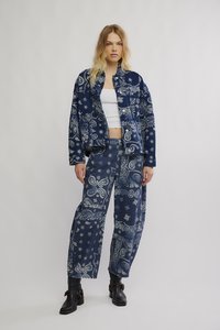 Tumesinise ja valgete paisleimustritega teksariidest jakk ja püksid, millel on lõdvestunud lõige, nööbid ja küljetaskud. Mustad pahkluu saabid.