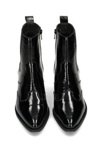 Botines de charol negro hasta el tobillo con puntera afilada, detalles decorativos de costura, cremalleras laterales y lazos en la parte posterior para facilitar su puesta.
