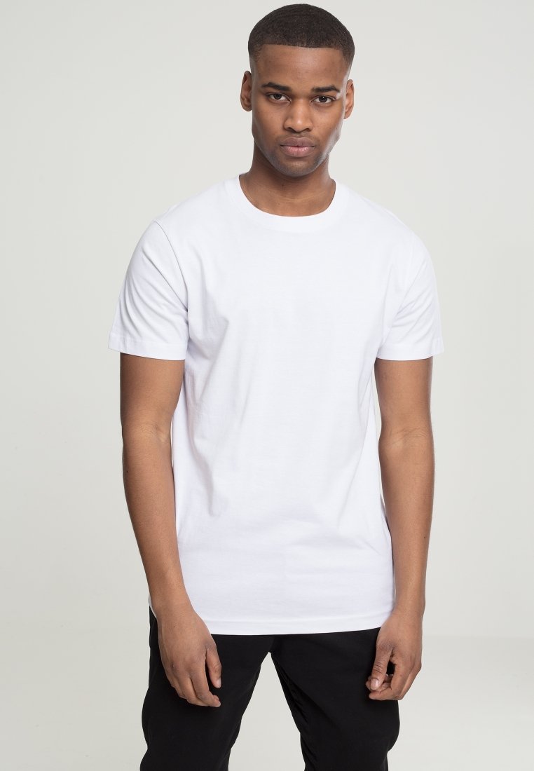 T-shirt alb din bumbac, cu guler rotund, mâneci scurte și croială largă. Materialul pare neted și ușor. Asortat cu pantaloni negri.