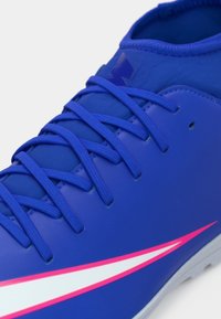 Μπλε ποδοσφαιρικά παπούτσια με λεία συνθετική επένδυση, που διαθέτουν ροζ και λευκές λεπτομέρειες, υφασμάτιρες κορδόνες και γκρι ελαστική σόλα.