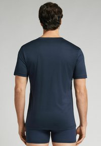 Granatowy t-shirt z krótkim rękawem wykonany z gładkiego materiału, z okrągłym dekoltem i luźnym krojem, w połączeniu z dopasowanymi szortami w tym samym kolorze.