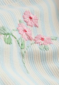 Tela suave con rayas en azul pastel, beige y blanco, con flores rosas bordadas con tallos y hojas verdes.