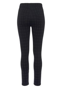 Schwarze Leggings mit einem karierten Muster in Gold. Sie haben ein enganliegendes Design, einen elastischen Bund und hinten Taschen. Glatte Textur, durchgehendem Schnitt.