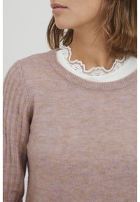 Maglione a ciniglia lilla con texture a coste sulle maniche. Un colletto in pizzo bianco a ondine spunta sotto.