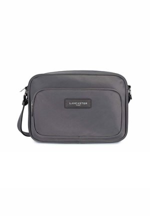 Borsa a tracolla grigia con una texture liscia, dotata di una tasca frontale, una patch con logo e una tracolla regolabile per comfort e funzionalità.