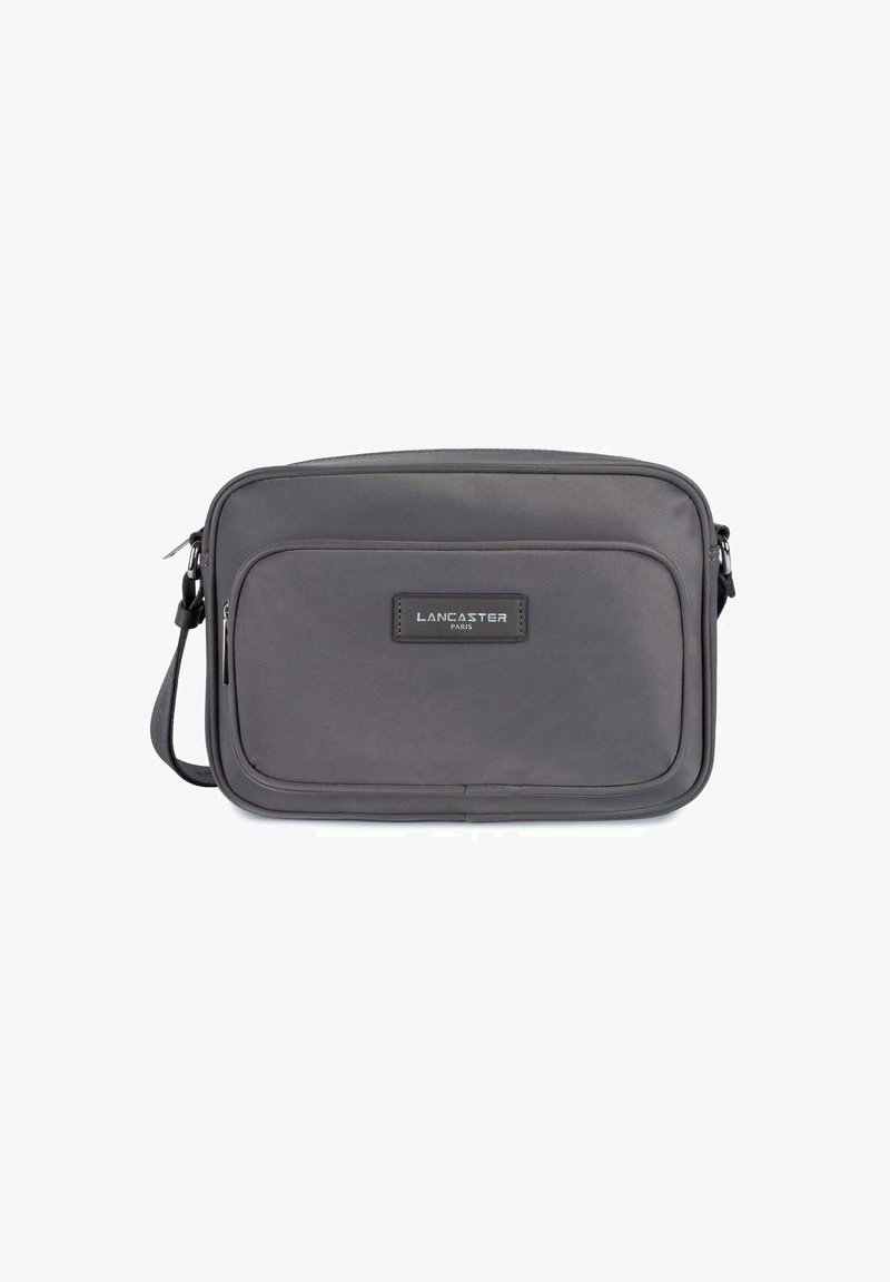 Borsa a tracolla grigia con una texture liscia, dotata di una tasca frontale, una patch con logo e una tracolla regolabile per comfort e funzionalità.