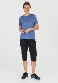 Blå träningströja med rund hals i kombinering med svarta, avkortade träningsbyxor och svarta sneakers, med en mjuk textur och minimalistisk design.