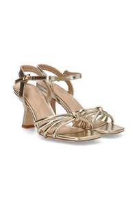 Sandalias de tacón alto metálicas doradas con punta cuadrada, que presentan múltiples correas cruzadas y una correa de tobillo ajustable. Textura suave.