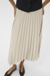 Gonna midi plissettata in beige chiaro, realizzata in un tessuto fluido. Il design presenta pieghe verticali e una forma svasata all'orlo, abbinata a scarpe nere.