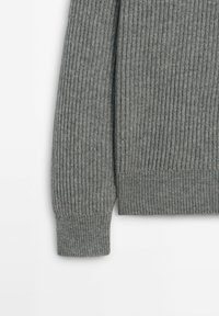 Manche et ourlet inférieur d'un pull en maille côtelée grise sur fond blanc, montrant la texture et le détail du poignet.