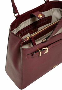 Borsa in pelle bordeaux con hardware dorato, tasca interna con zip e accentuazione con fibbia sul davanti. Foderata in tessuto chiaro.