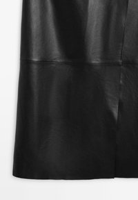 Sort nederdel i imiteret læder med syede vandrette og lodrette sømdetaljer mod en hvid baggrund.